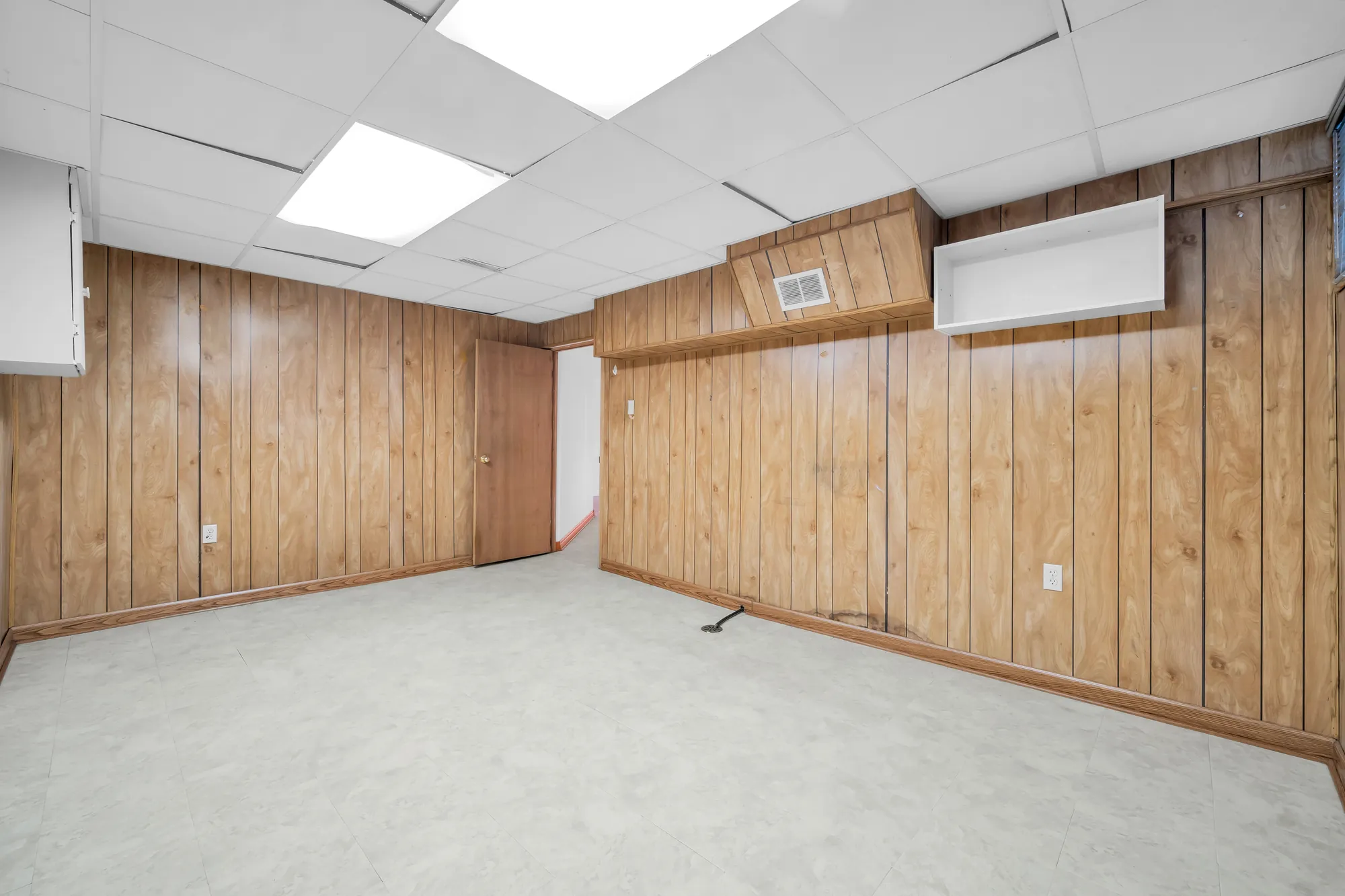 The same room toward its door, the panelled walls and a white cabinet