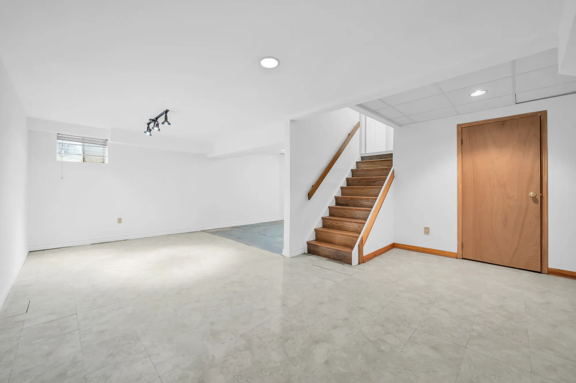 The basement toward the stair up to the main floor, a wood door at the right, a small window