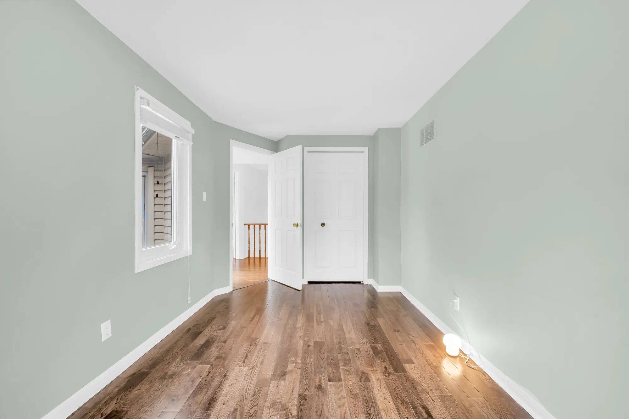 The green bedroom toward its door and closet, a window at the left