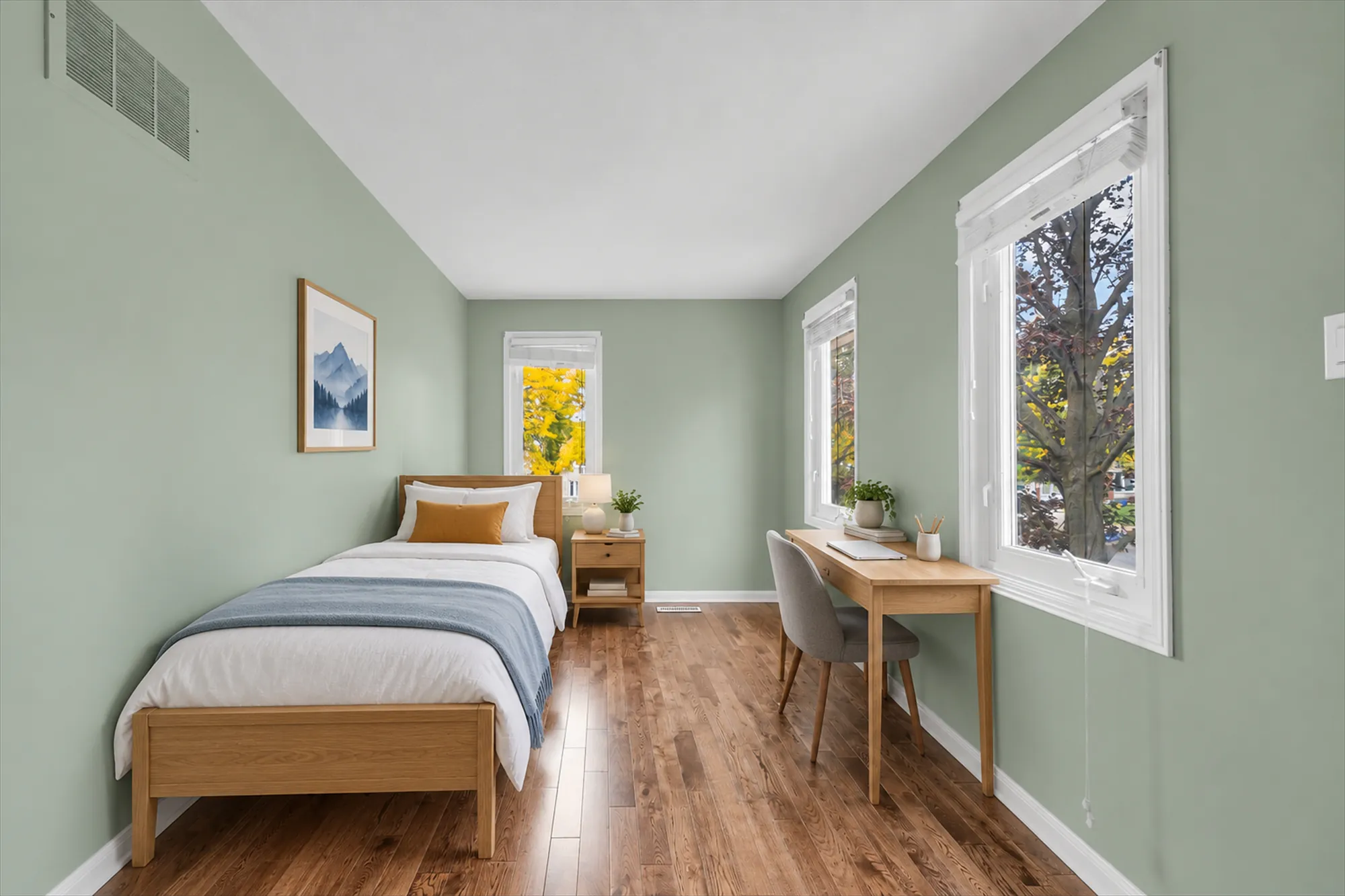 The same frame virtually staged: a single bed with a blue throw, a night table and lamp, a desk and chair under the side window, a framed print