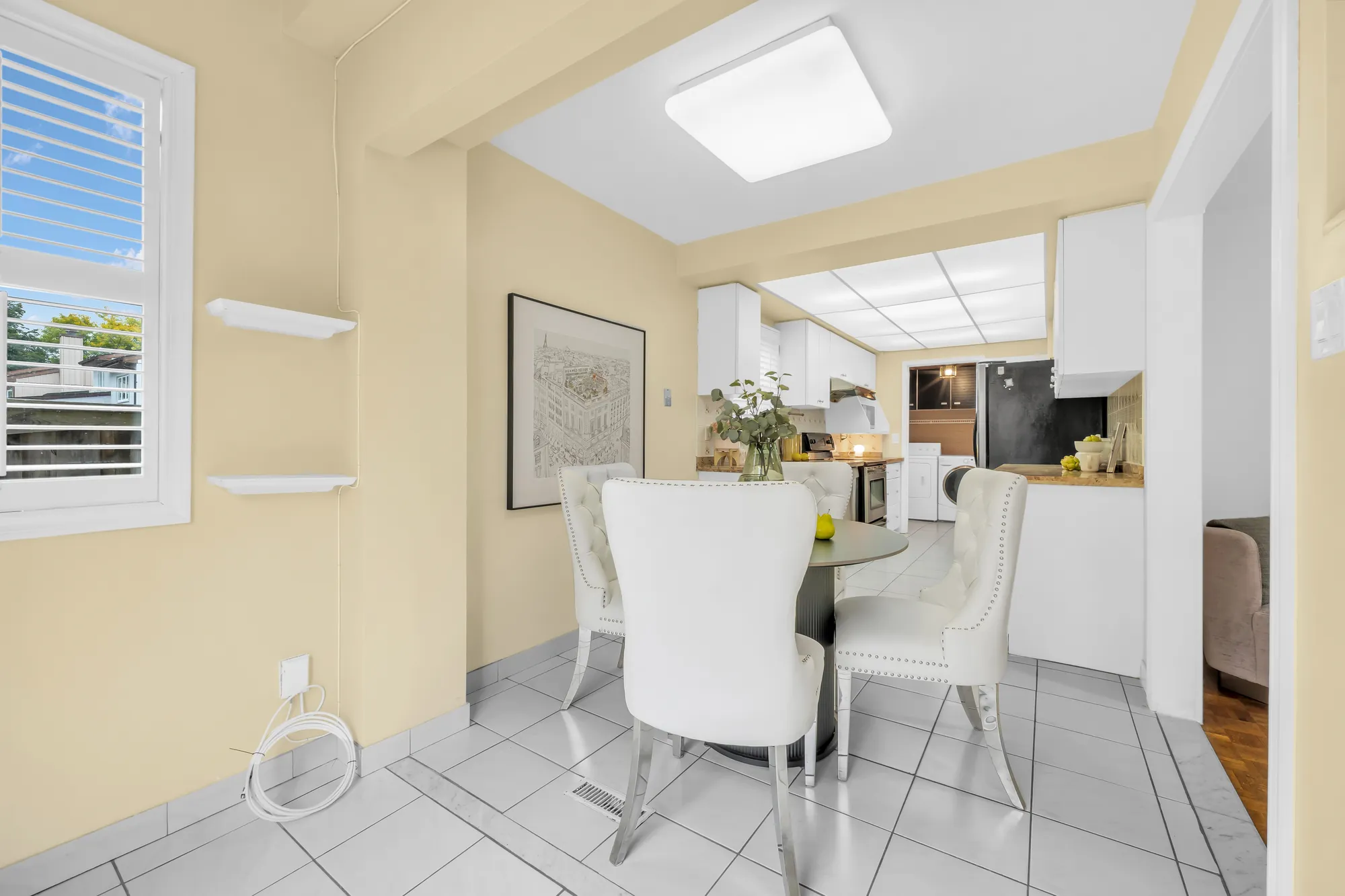 The breakfast room toward the kitchen, a window with shutters at the left, the table and chairs
