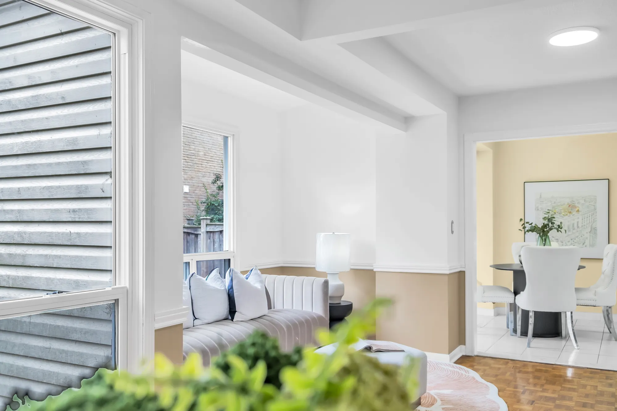 Past a window and a plant to the sitting area and the breakfast room table