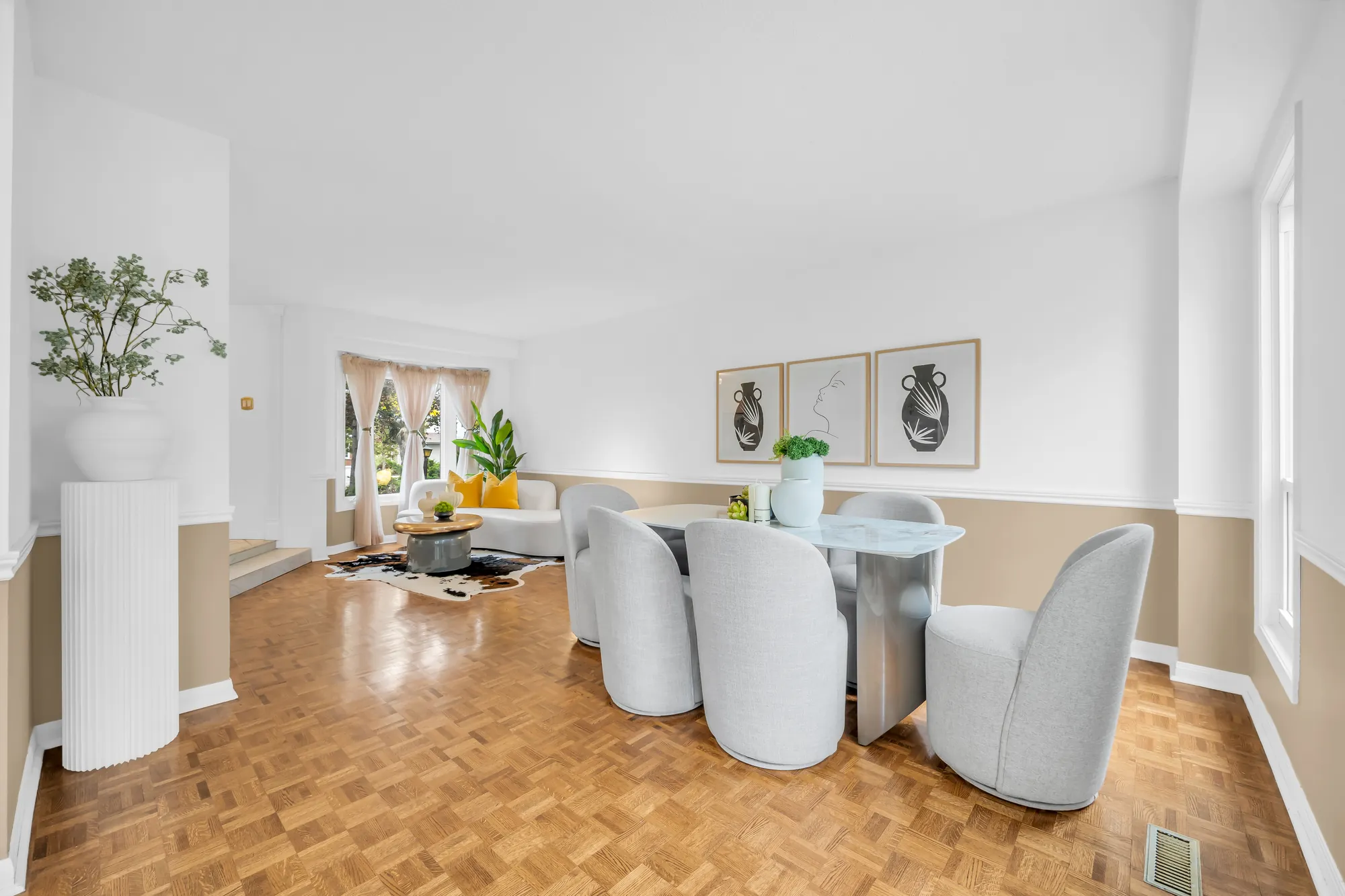 The dining area and the living room from the far corner, the bay window at the front, parquet floors throughout