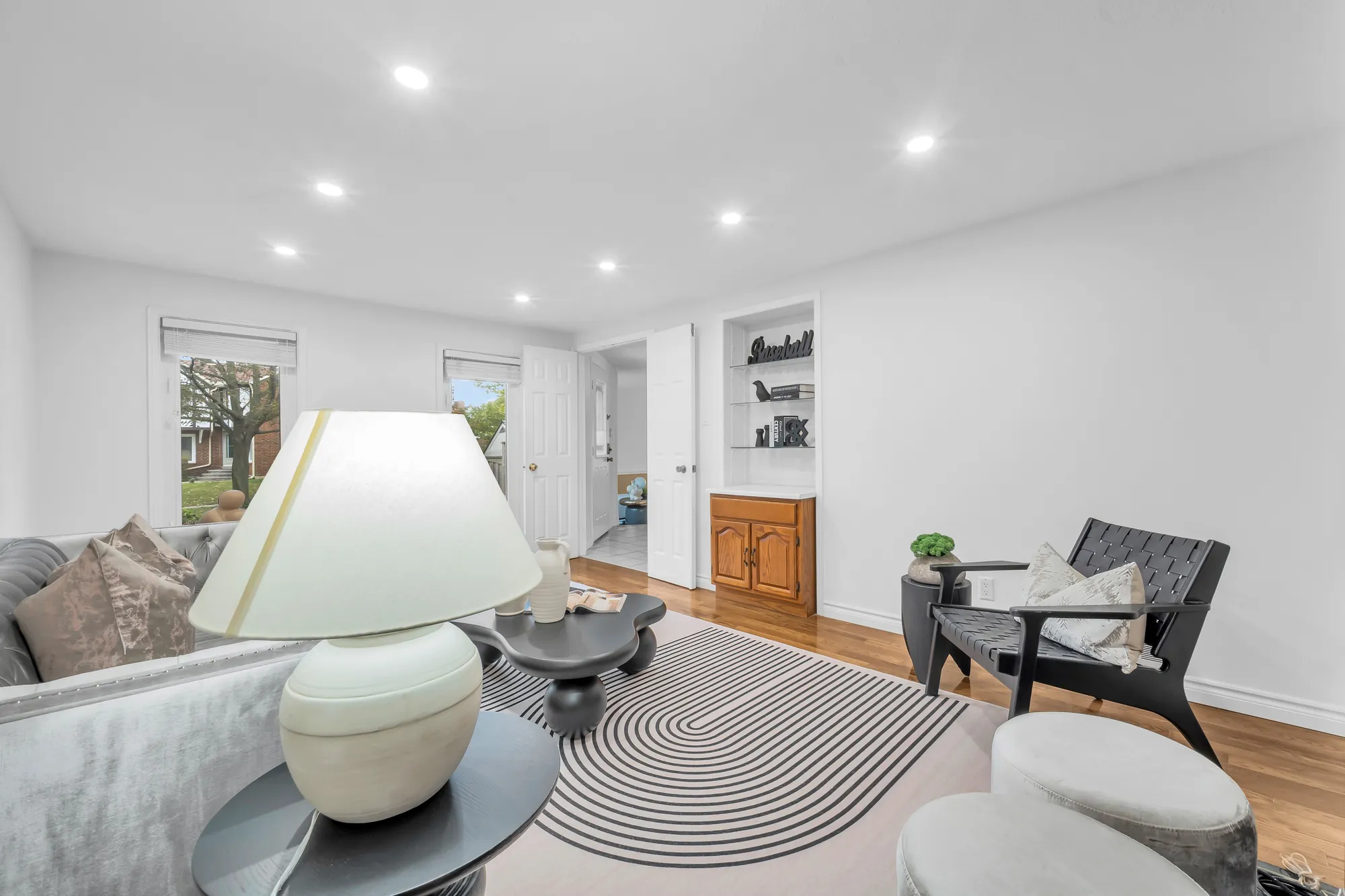 The family room toward its windows onto the street, a built-in shelf and cabinet, the hall through the doorway