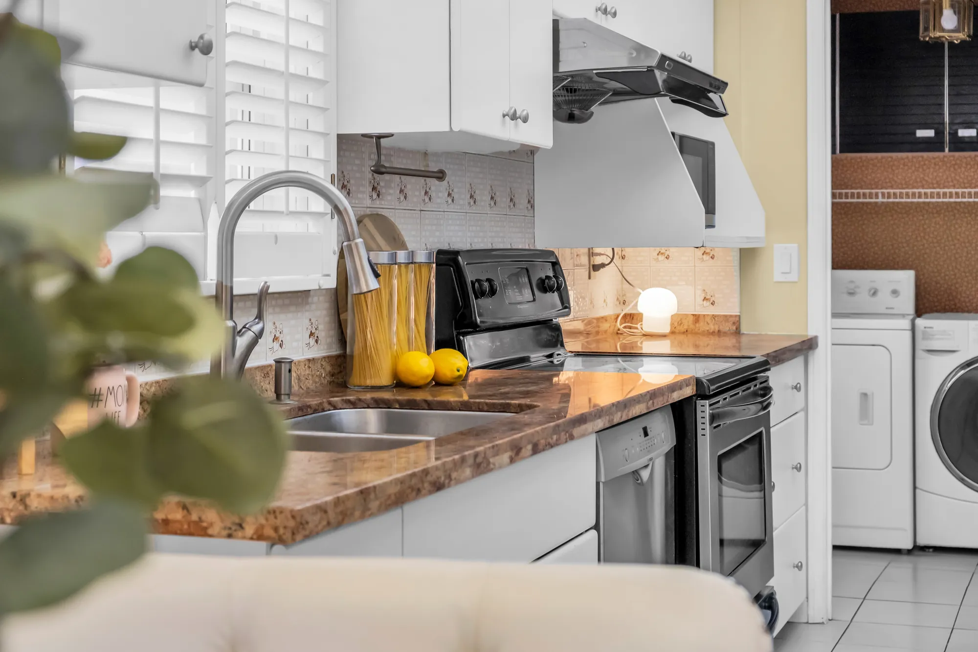 The sink, the range and the dishwasher, the laundry room through the doorway at the right