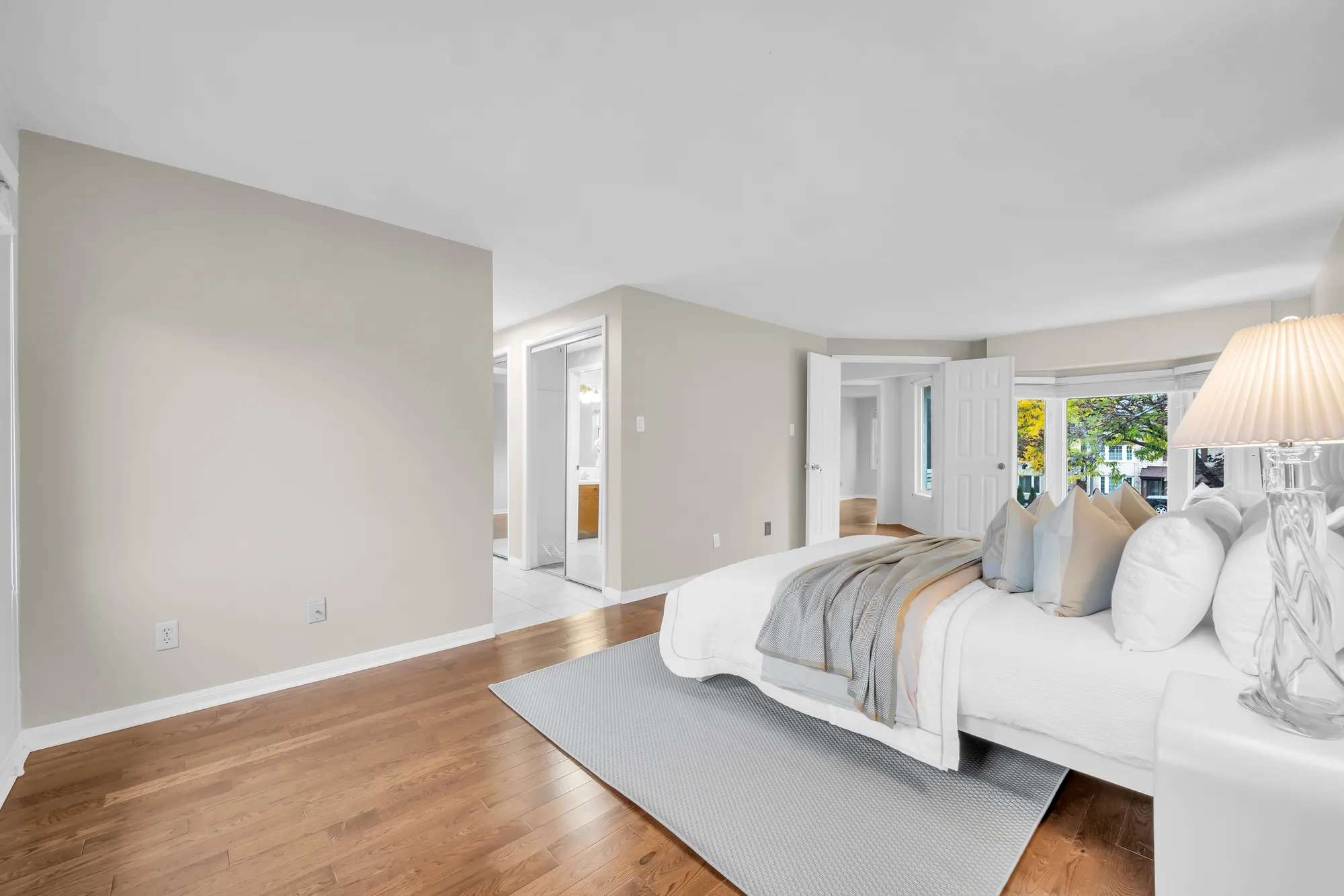 The primary bedroom from the windows toward the doors to the closets and the hall