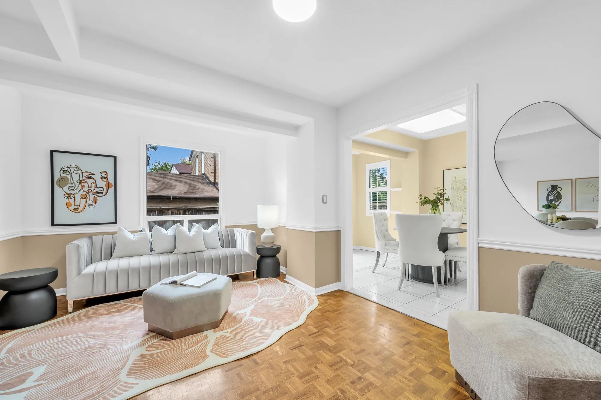 The sitting area toward the breakfast room, a mirror and framed print on the walls, a lounge chair in the foreground